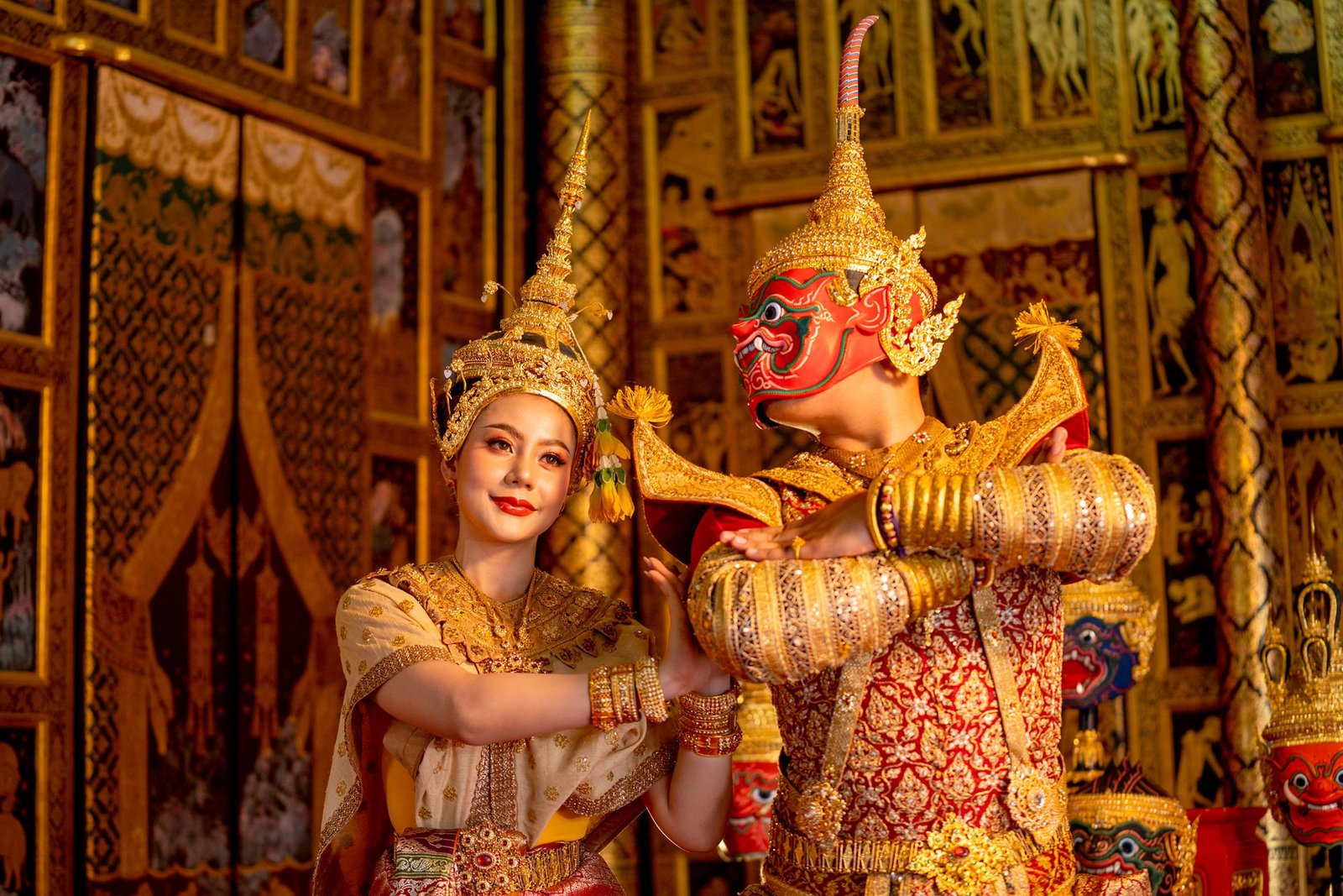 Two Khon dancers in gilded costume and mask performing Thai classical masked drama